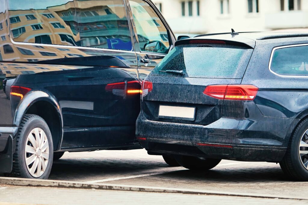 Two vehicles involved in a rear-end collision on city street, showing car accident damage for auto insurance claim and traffic incident.