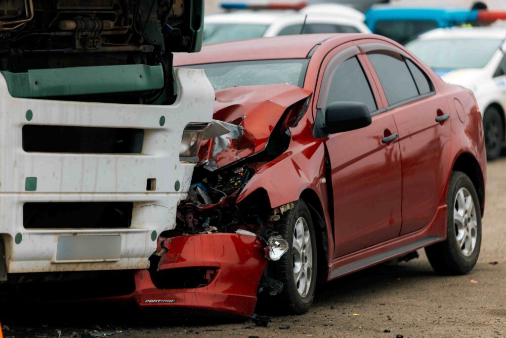 Severely damaged red car after rear-end collision with a truck, illustrating a serious traffic accident and vehicle crash scene.