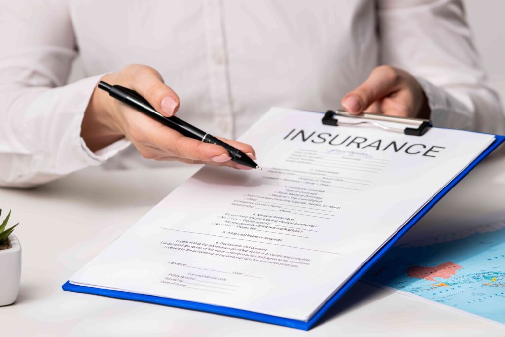 Person holding pen and reviewing an insurance policy form on clipboard, representing insurance claim documentation and coverage agreement.