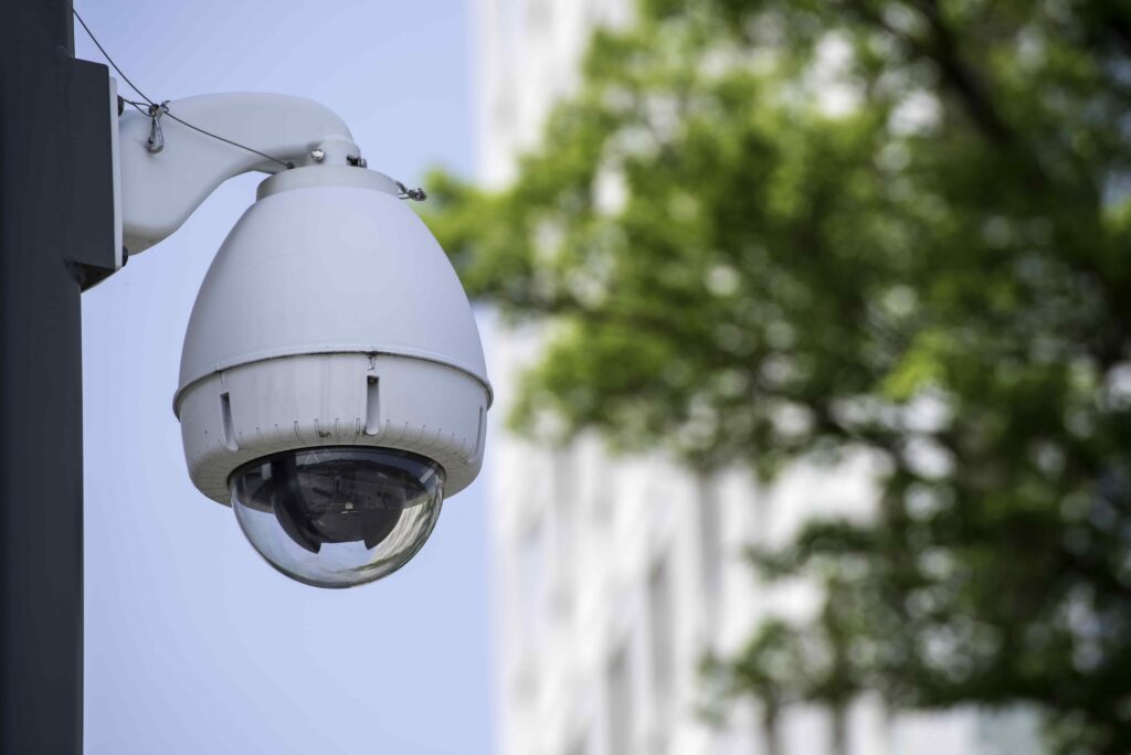 Outdoor security surveillance camera mounted on a pole monitoring a city street for public safety.
