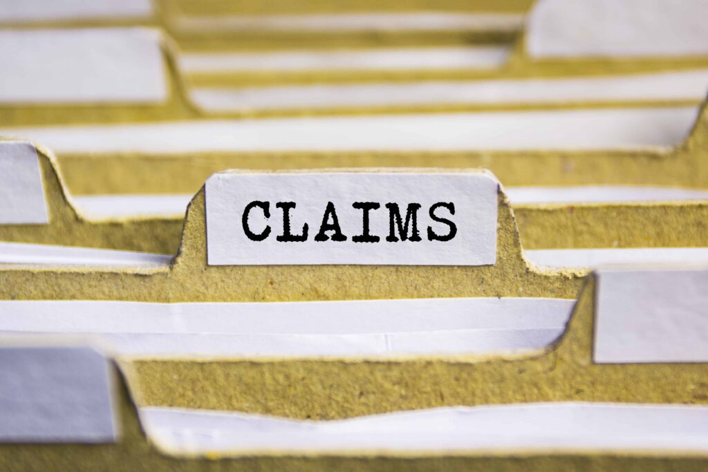 File folder tab labeled &ldquo;Claims&rdquo; representing insurance claims paperwork and legal case documentation.