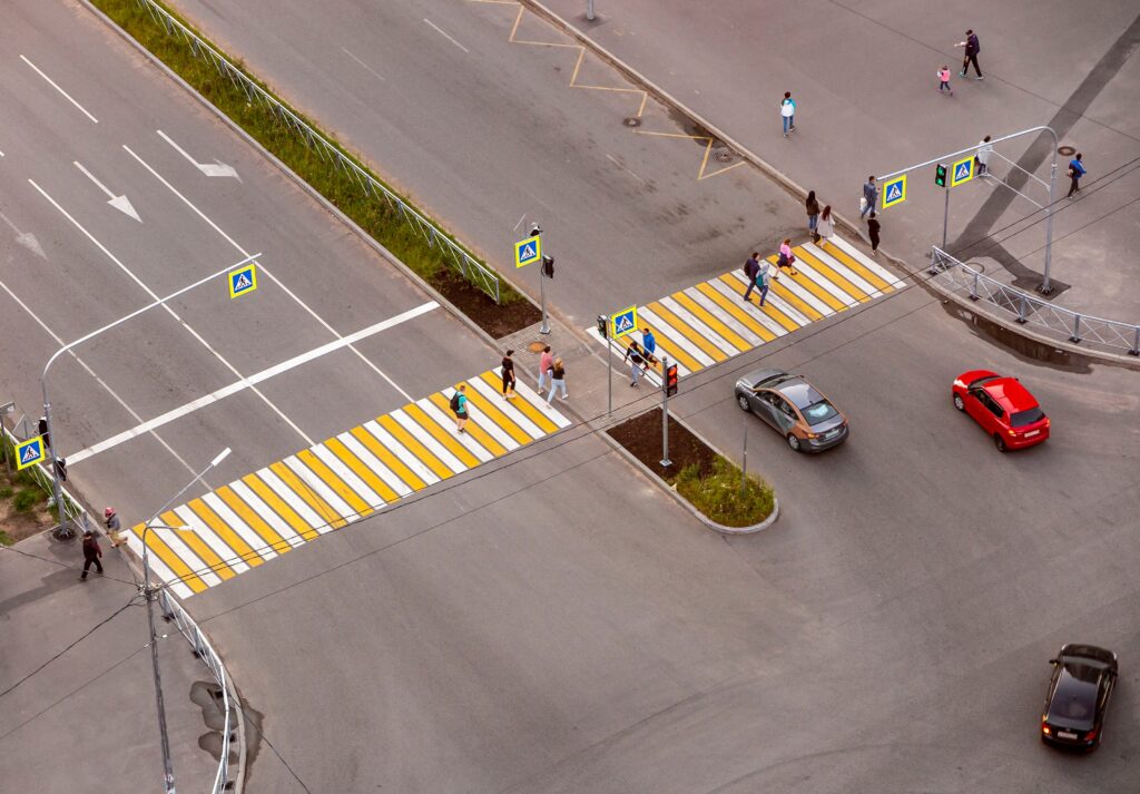 Aerial view of pedestrians crossing a Texas intersection at marked crosswalks while vehicles wait under pedestrian right-of-way traffic laws