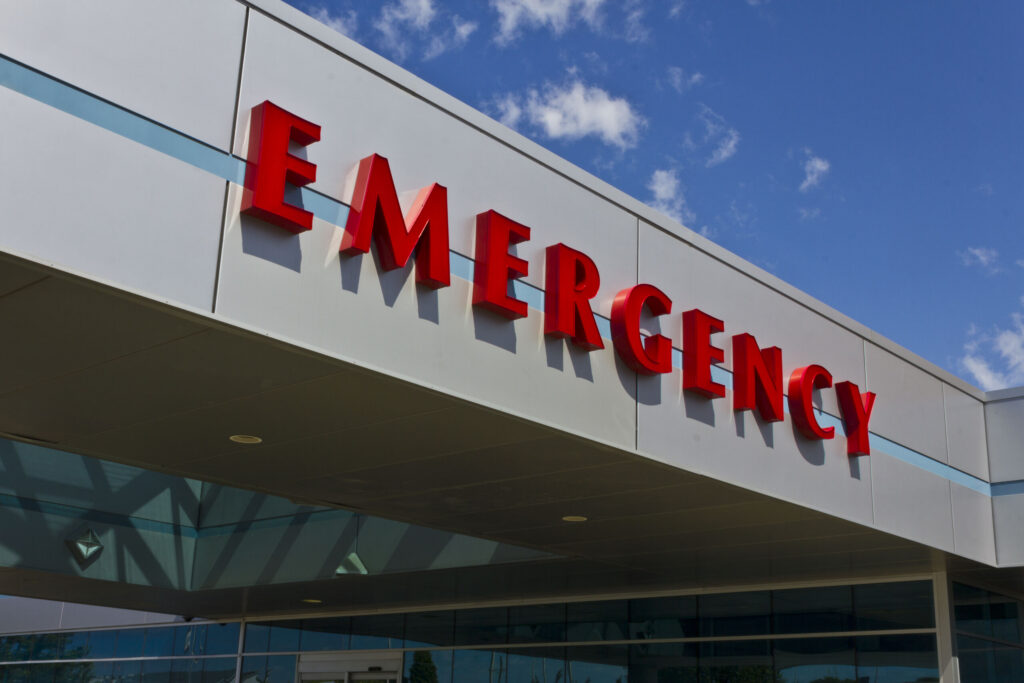 Large red emergency sign on a hospital building exterior, highlighting immediate medical care before creating life care plans for Texas catastrophic injury.
