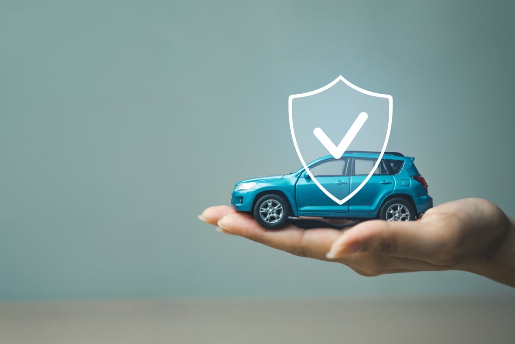 A hand holding a small toy blue car with a digital shield and checkmark graphic overlay, symbolizing protection and auto coverage under Texas Uninsured Motorist Accident Lawyers.