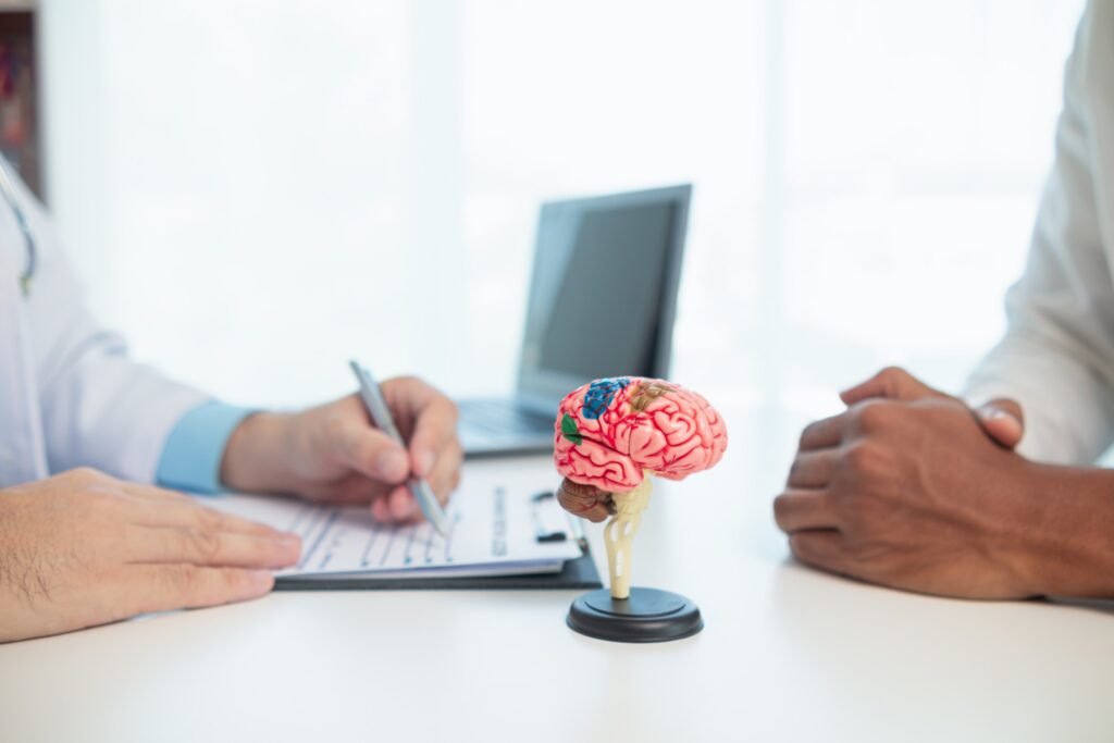A medical professional points to a color-coded brain model during a consultation with a patient, outlining details for the lifetime cost of a TBI in Texas & your claim.