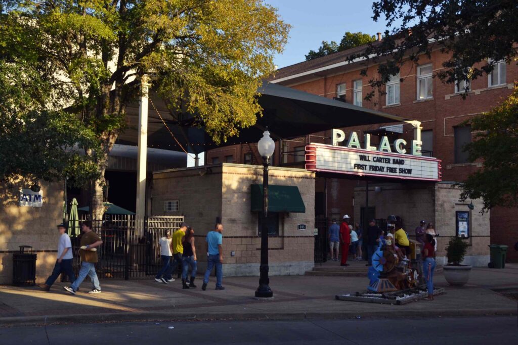 People walking past the historic Palace Theater in downtown Bryan represent the community served by Bryan Personal Injury Lawyers.
