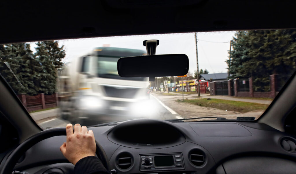 A driver's view from inside a car showing a semi truck approaching on the road, highlighting why victims need College Station Truck Accident Lawyers.