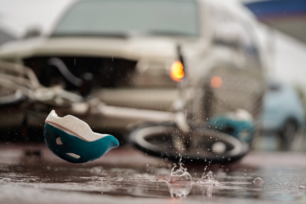 A bicycle helmet lying on a wet road next to a crash scene illustrates the focus of A Cyclist's Guide to Texas Road Rules and Injury Claims.