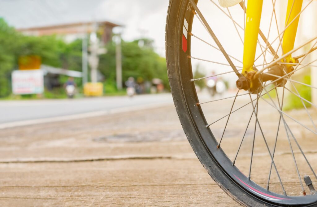 A close up view of a bicycle wheel on the roadside highlights key concepts in A Cyclist's Guide to Texas Road Rules and Injury Claims.