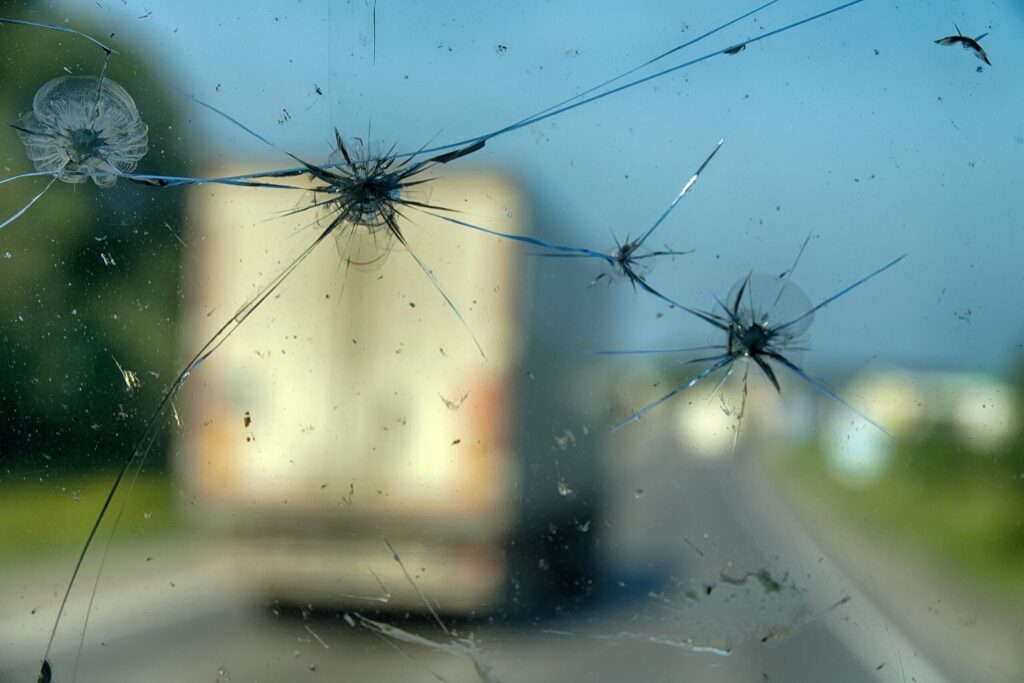 Cracked windshield looking at a semi-truck on a Texas highway.