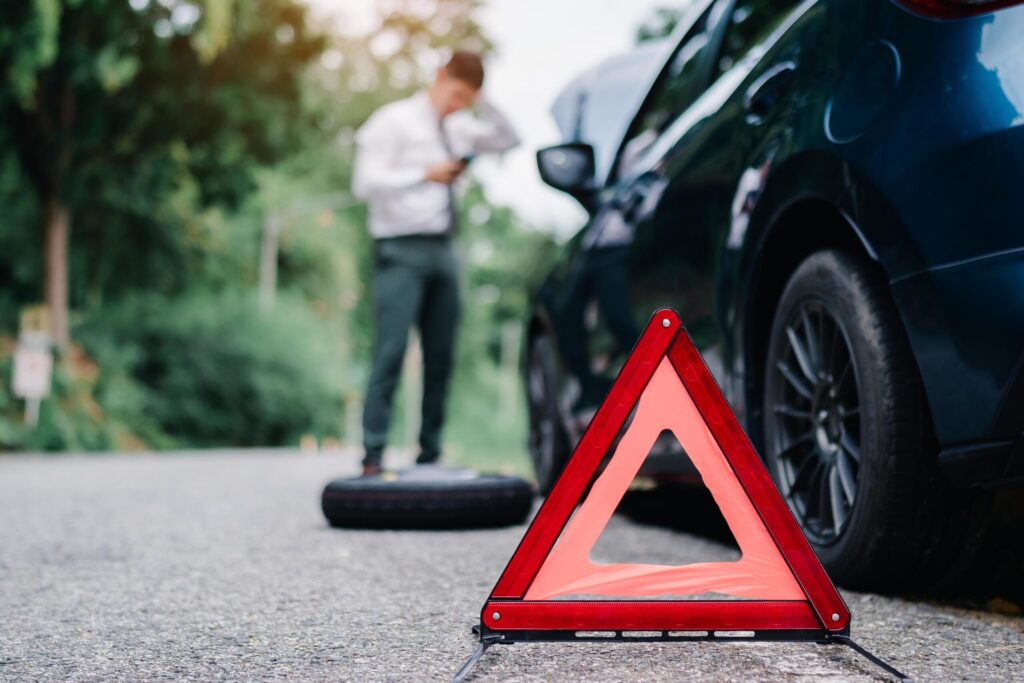 Warning triangle on roadside with stressed driver near disabled car after San Antonio accident.