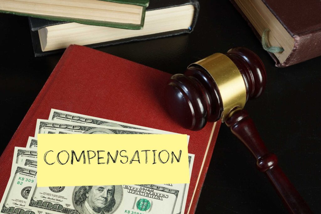 A gavel and currency with a "COMPENSATION" tag on a red book represent the legal details of Texas Spinal Cord Injury Claims: What Compensation Covers
