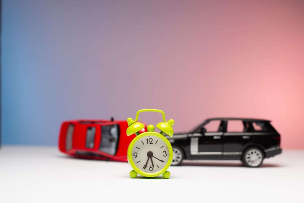 Green alarm clock in front of toy cars representing deadlines for Texas wrongful death claims.